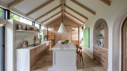 A converted barn turned into a large kitchen with vaulted ceilings, a neutral color palette, and wooden accents