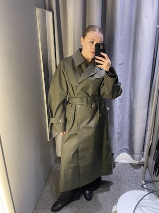 Woman wears green trench coat from Arket