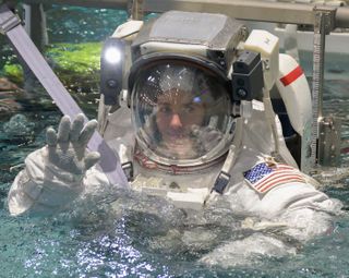 an astronaut in a spacesuit waving in a pool