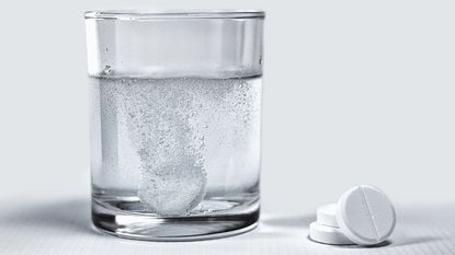 A denture tablet fizzing in a glass