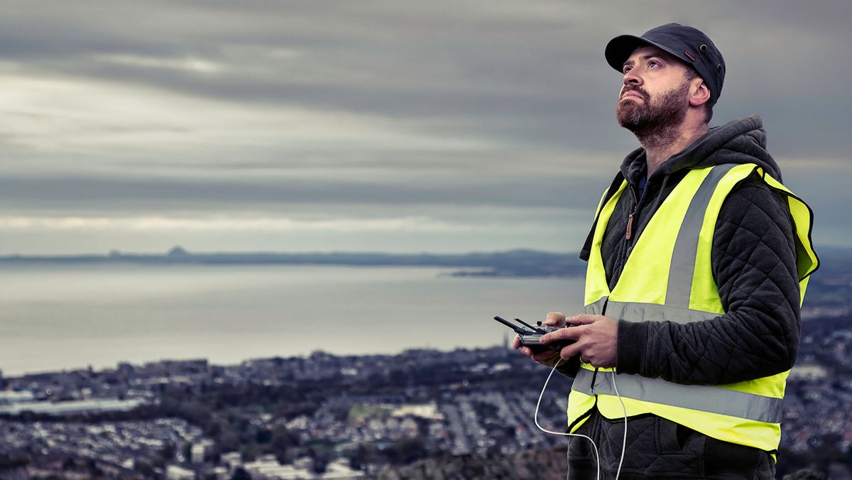 Drone pilot Andy Smith operating drone with cityscape and bay in background