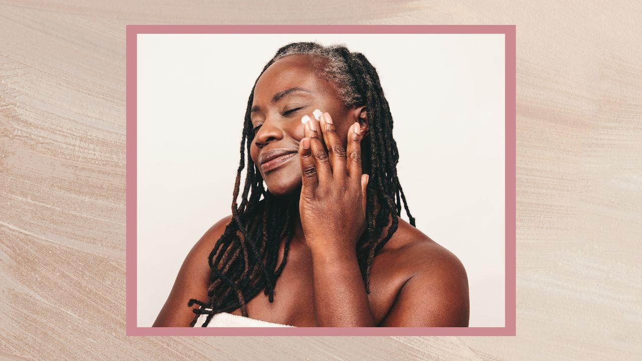 A woman is pictured applying face cream to her cheek with her fingers, whilst wearing a towel/ in a cream /taupe textured template