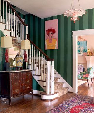 Green striped entryway with dark wooden flooring and vintage furniture and rug