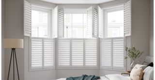 Neutral decorated bedroom with wooden window shutters to show how to get the quiet luxury aesthetic in any room