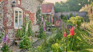 flint stone cottage with gardens planted to lawn and heavily planted borders