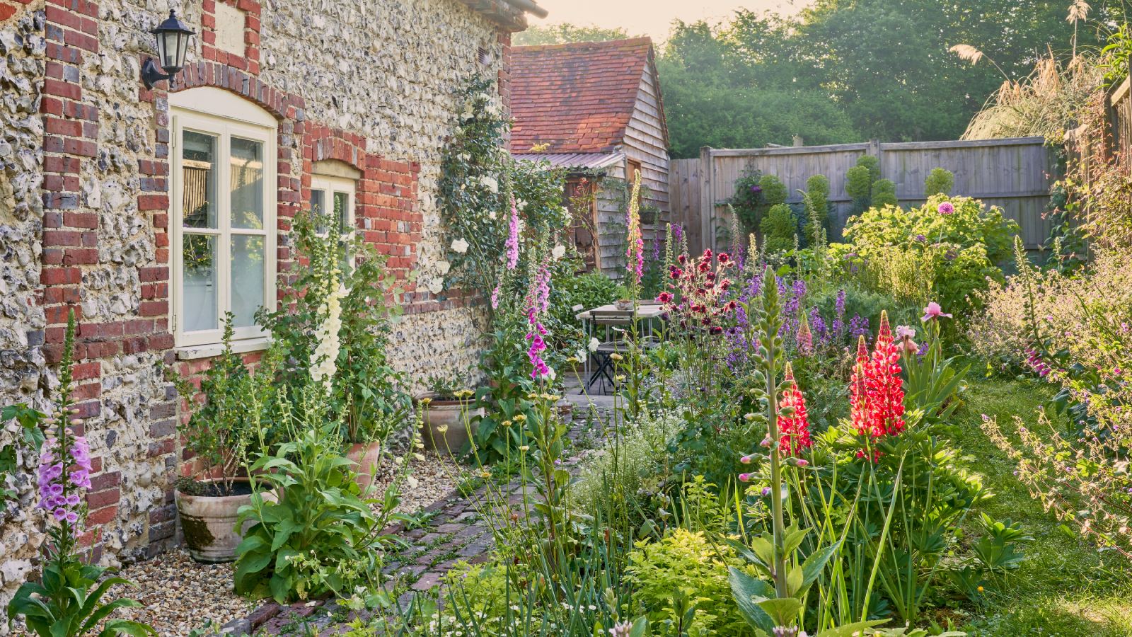 flint stone cottage with gardens planted to lawn and heavily planted borders