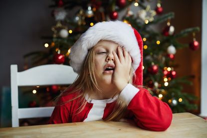 A child in a Christmas hat looking tired