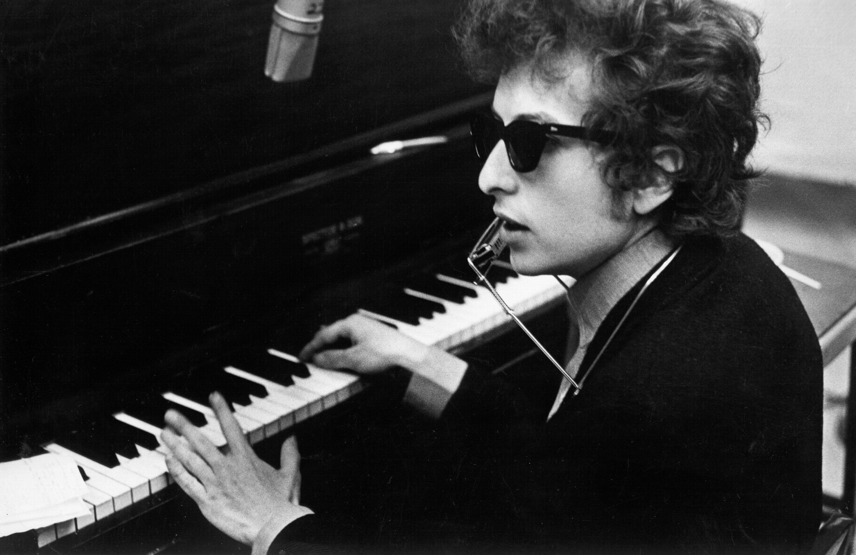 Bob Dylan plays piano with a harmonica around his neck during the recording of the album 'Highway 61 Revisited'