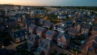 View over London of homes with solar panels with a sun setting in the distance