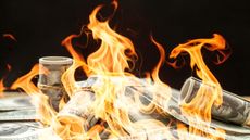 A pile of rolled-up money is on fire.