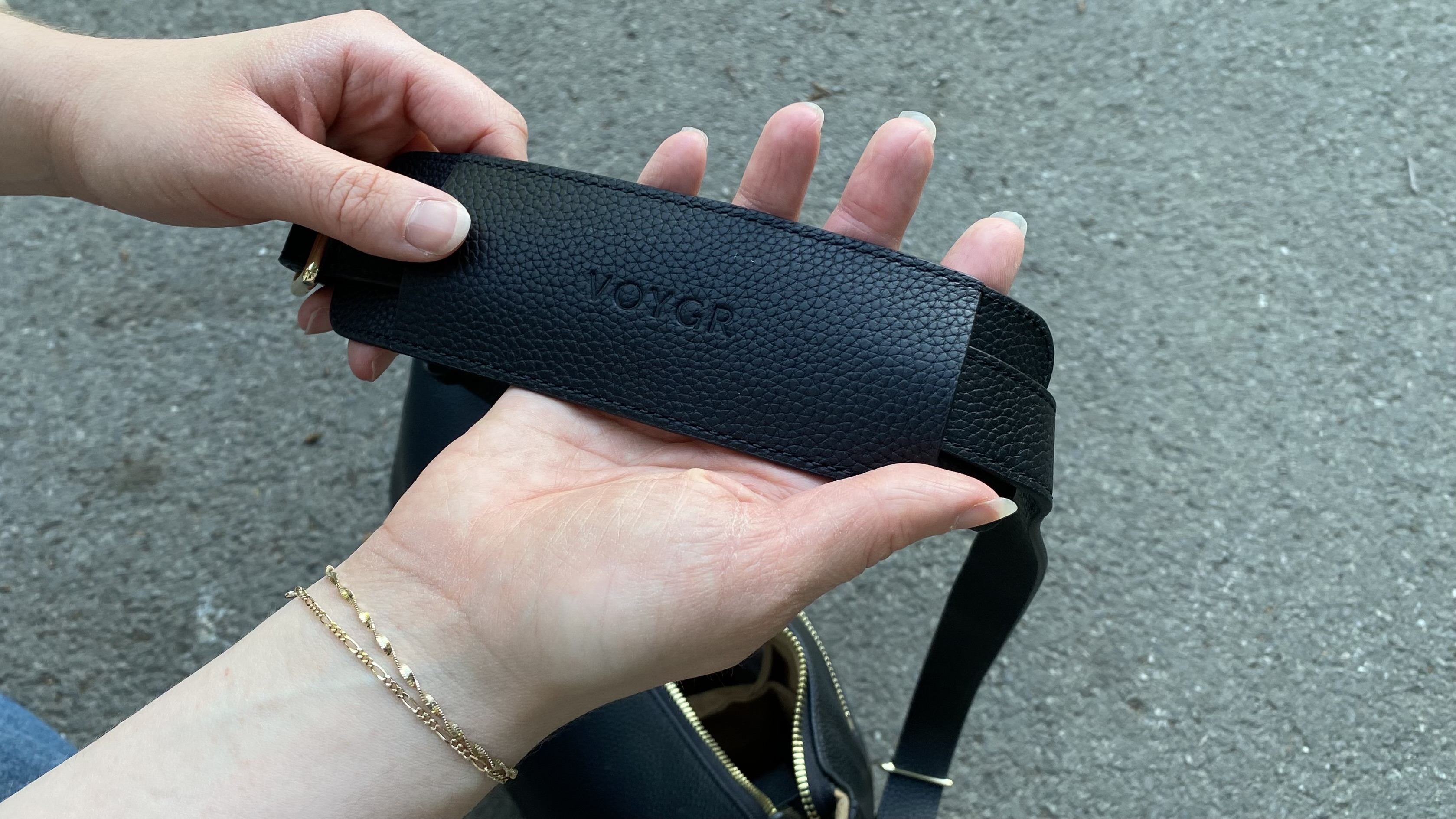 Person examining Voygr 1 camera bag strap
