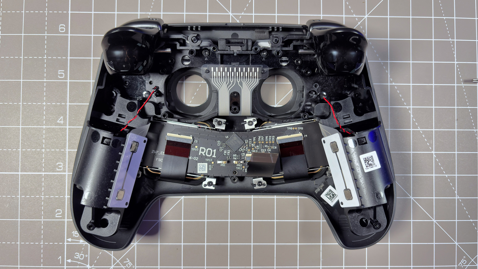 The Steam Controller on a desk during a teardown, with various parts removed.