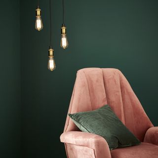 room with green wall and pink arm chair with cushion