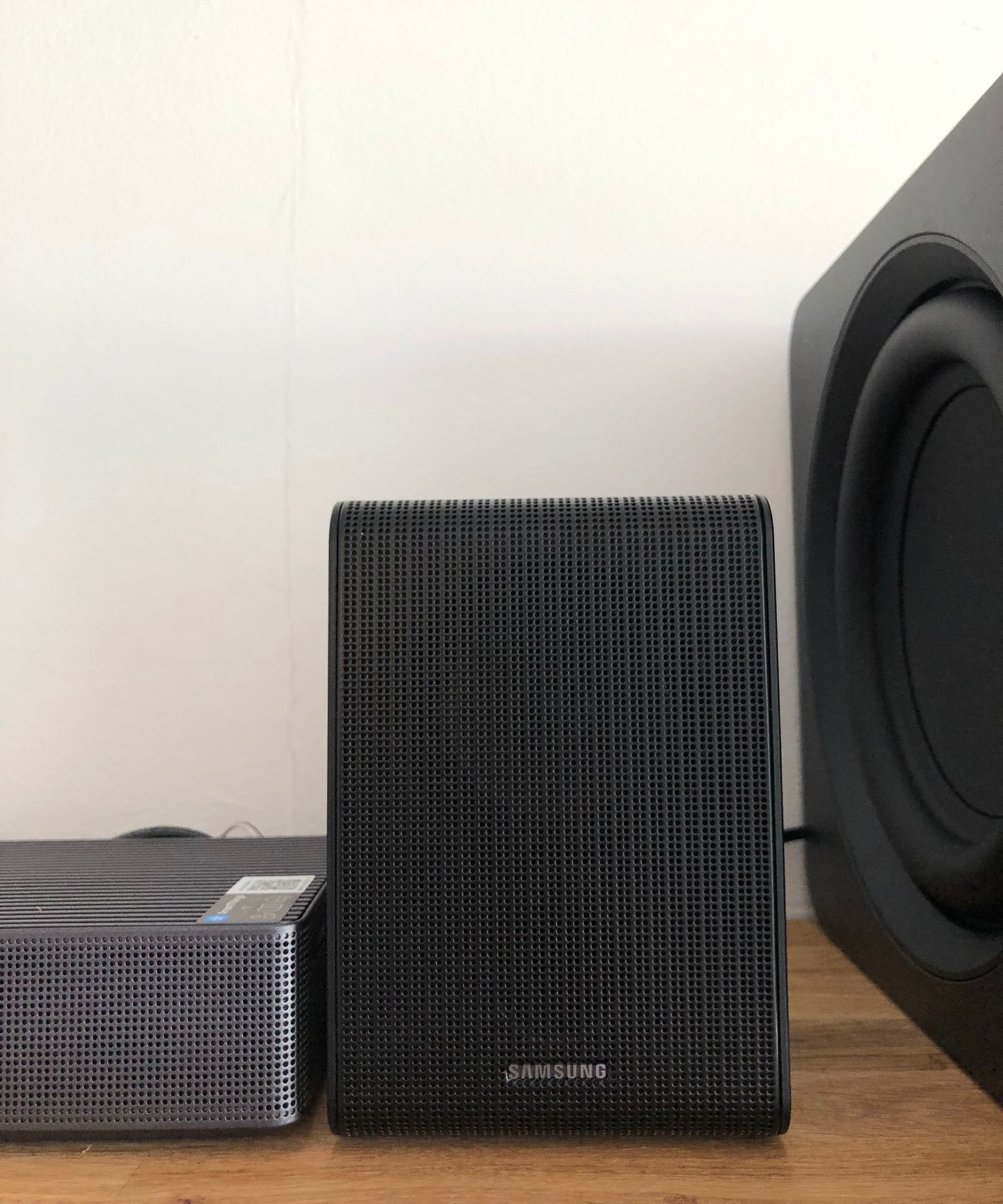 Closeup of surround speaker of Samsung HW-QS750F soundbar on wooden shelf in Dan Fauzi&#039;s home.
