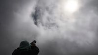 A photographer takes a picture of the sun through the clouds at the Villarica volcano sky center refuge, in Pucon, Chile on December 13, 2020.