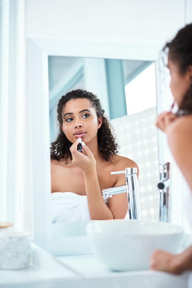 A woman applying lipstick in the mirror