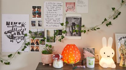 Bedroom with hanging photos, vines, and lights with decorative items on shelf