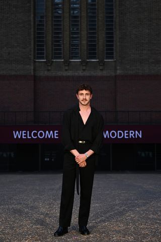 Paul Mescal in a low-cut black blouse and black pants at the Gucci Cruise 2025 show.