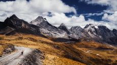 A cyclist tours on flat roads below mountains 