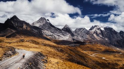 A cyclist tours on flat roads below mountains 