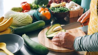 woman cutting an avocado to make a healthy salad