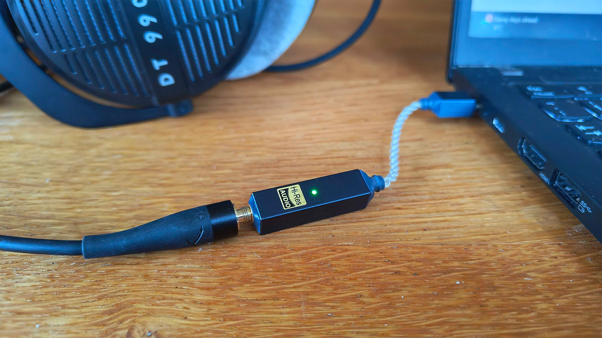 iFi Go Link 2 DAC on wooden table connected between laptop and Beyerdynamic headphones