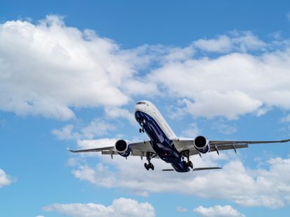 Close up tracking shot of plane coming into land with blue cloudscape behind.