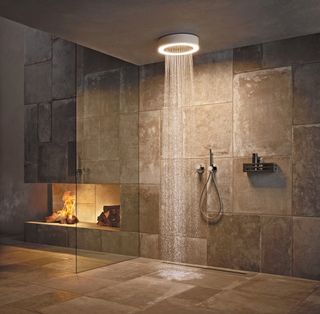 A waterfall shower with an inbuilt lED light in the shower head inside a bathroom with a fireplace