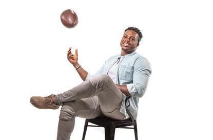 NFL linebacker Brandon Copeland sitting in a chair tossing a football in the air.