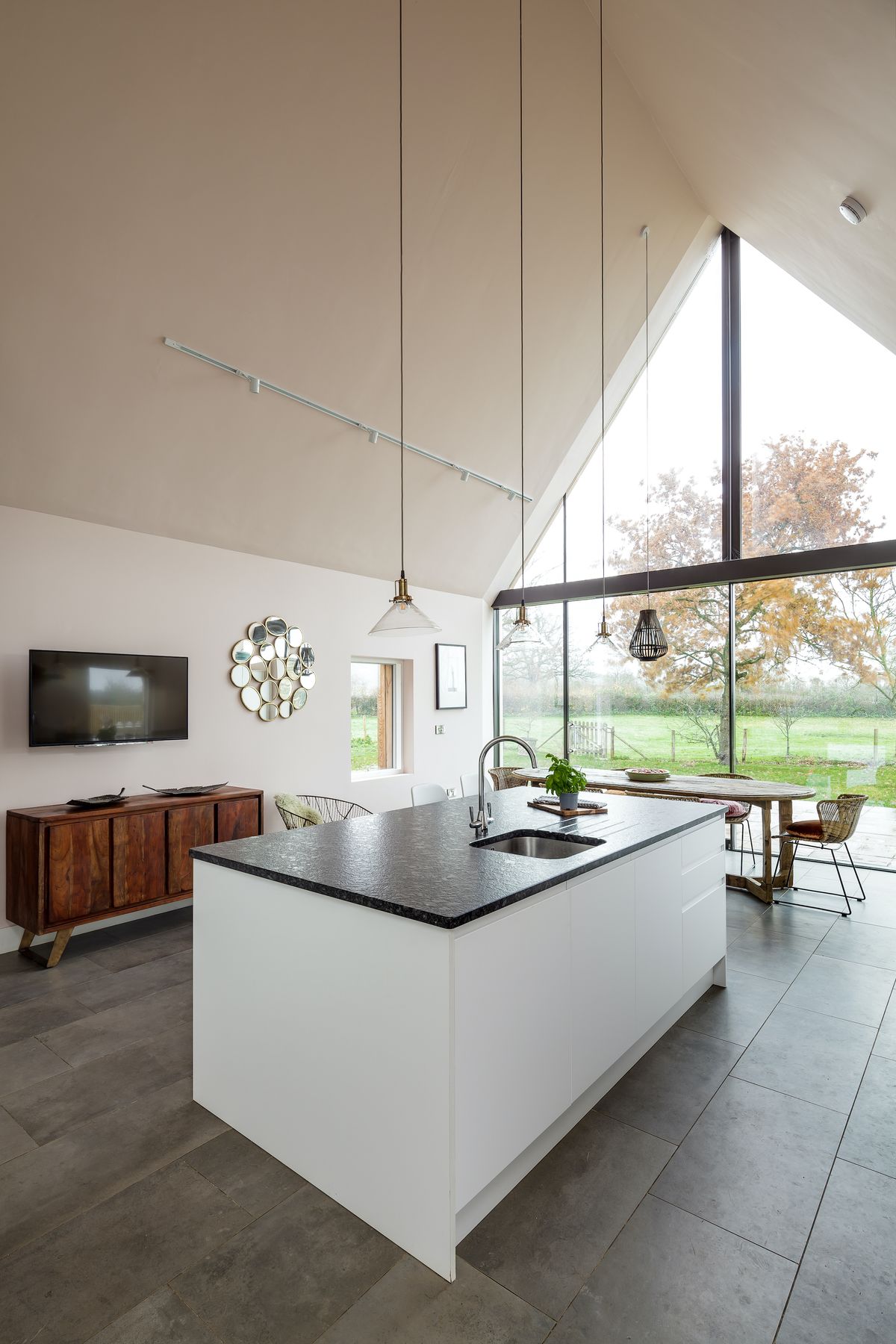 The contemporary-style kitchen units are from Howdens, and the large-format grey floor tiles are from Mandarin Stone.