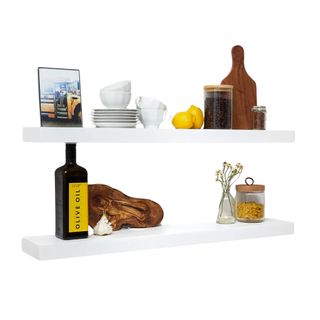Two white floating shelves with kitchen products on it