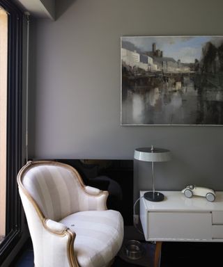 gray corner of room with white armchair, artwork on wall and white sideboard