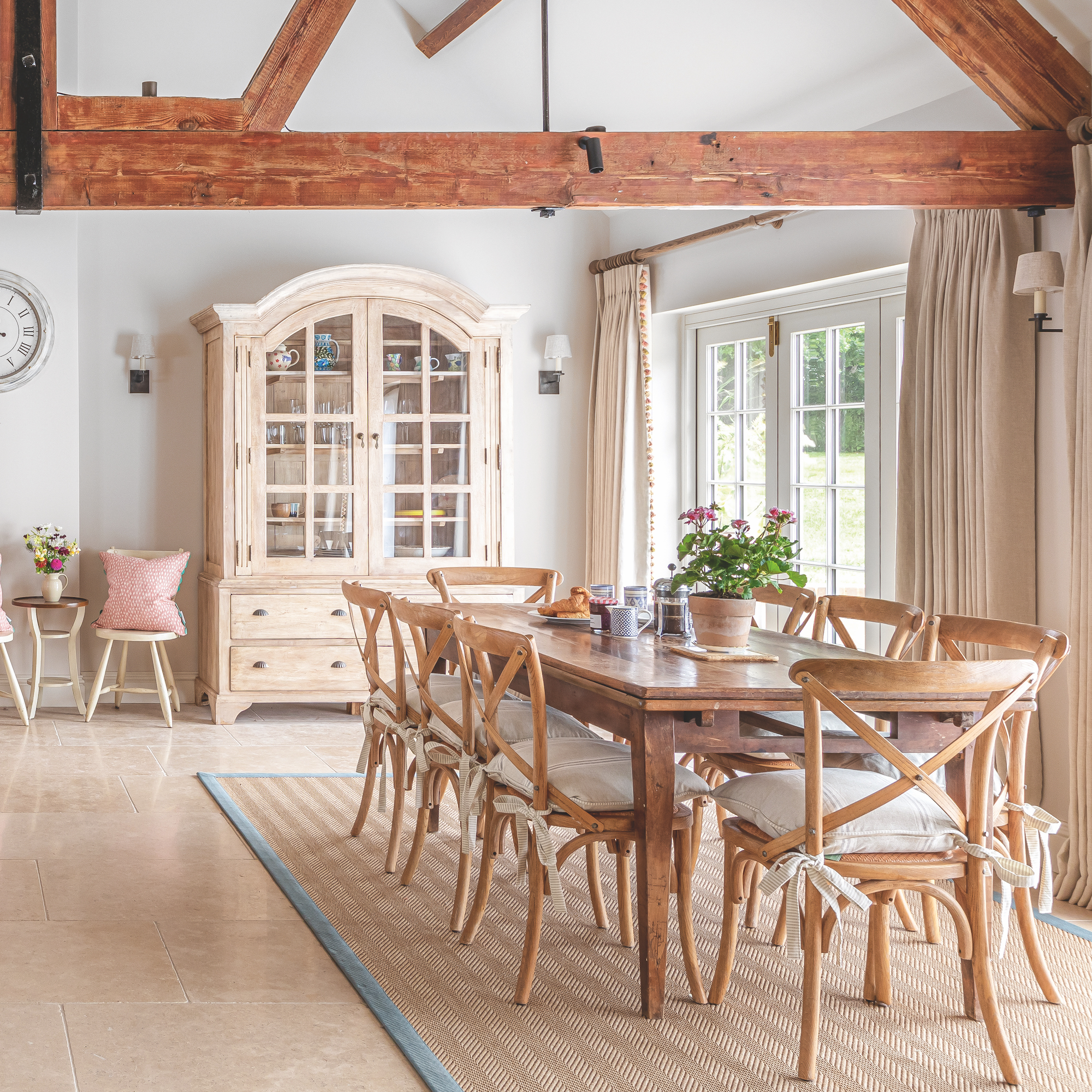 dining area in barn conversion with large wooden table surrounded by dining chairs and large glazed cabinet