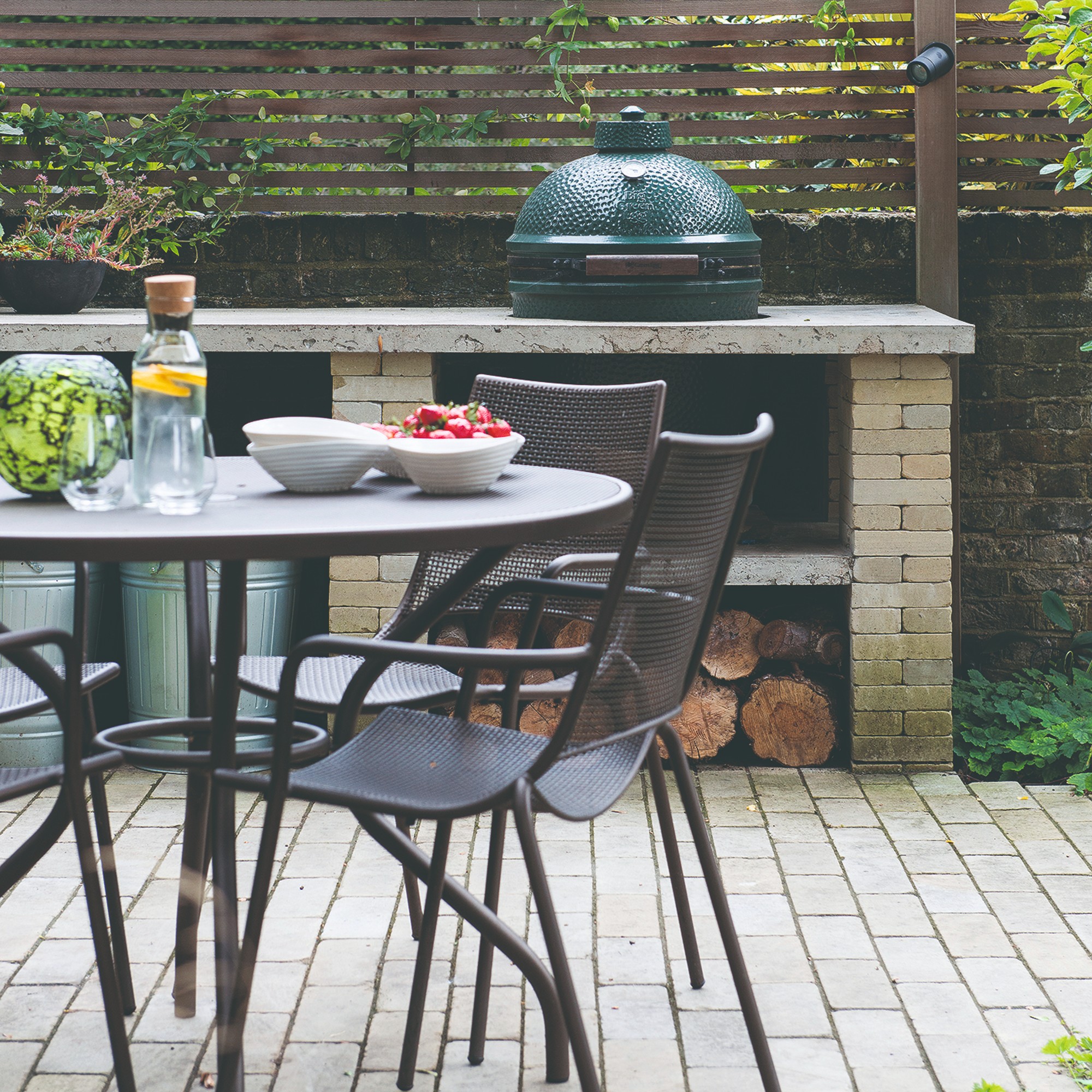 A garden furniture set with an outdoor kitchen in the background