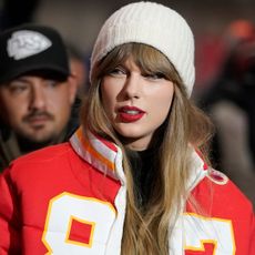 Taylor Swift attends a chiefs game wearing a custom puffer jacket and a beanie