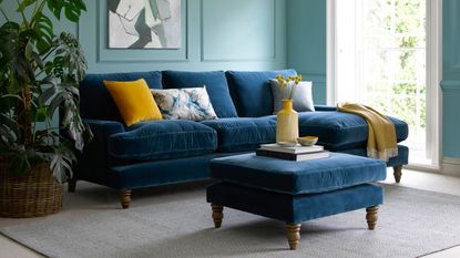 Living room with blue sofa and blue footstool in foreground