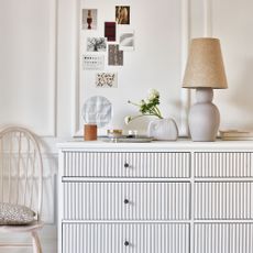 white chest of drawers with white fluted detailing and lamp