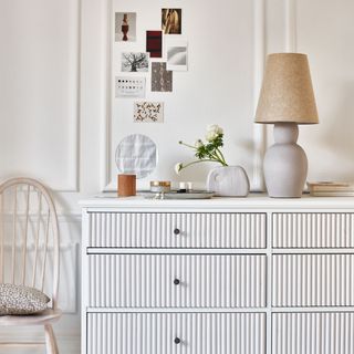 white chest of drawers with white fluted detailing and lamp