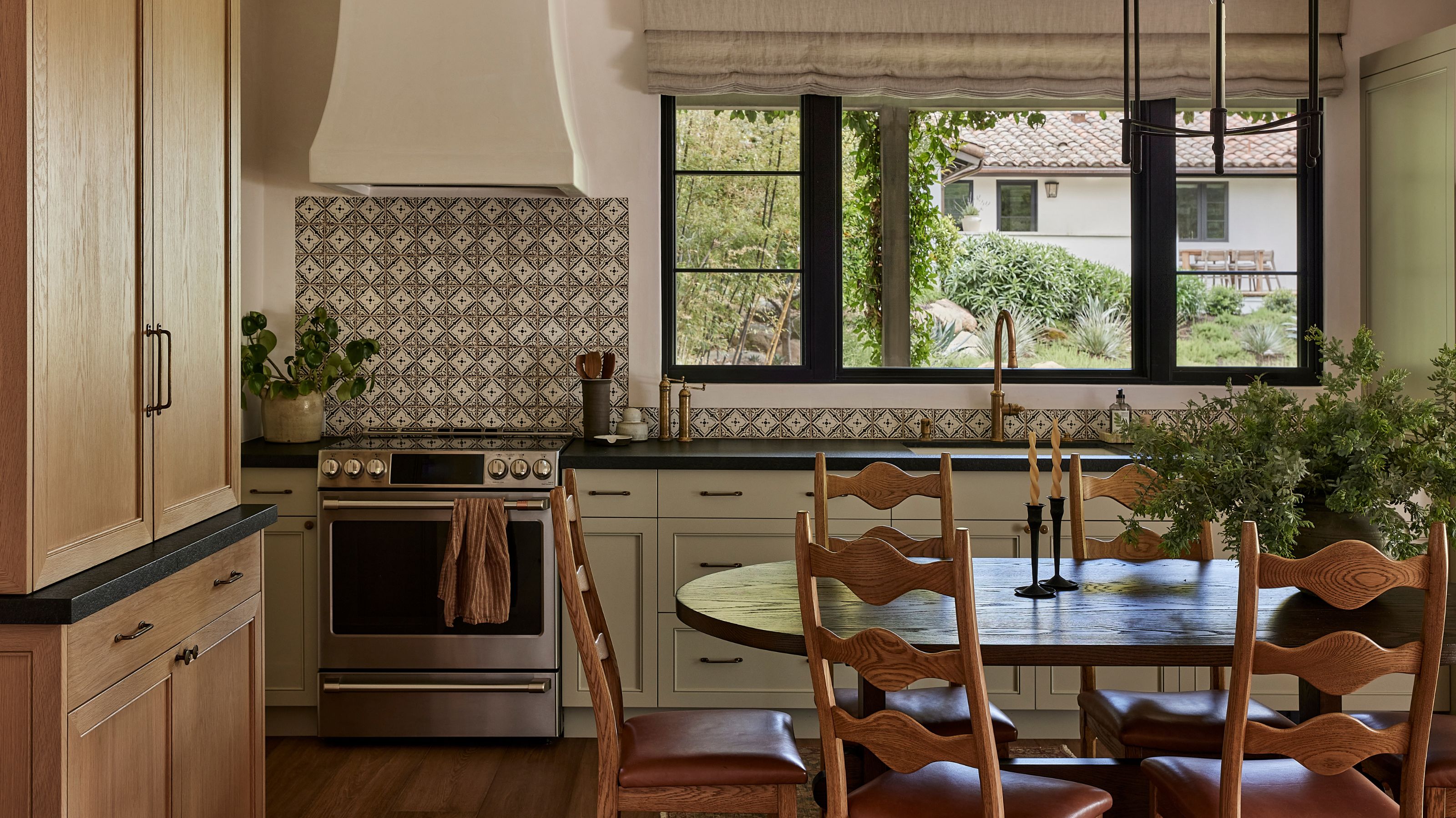 a small kitchen in a casita guest house with printed tiles, wooden cabinetry and vintage table and chairs