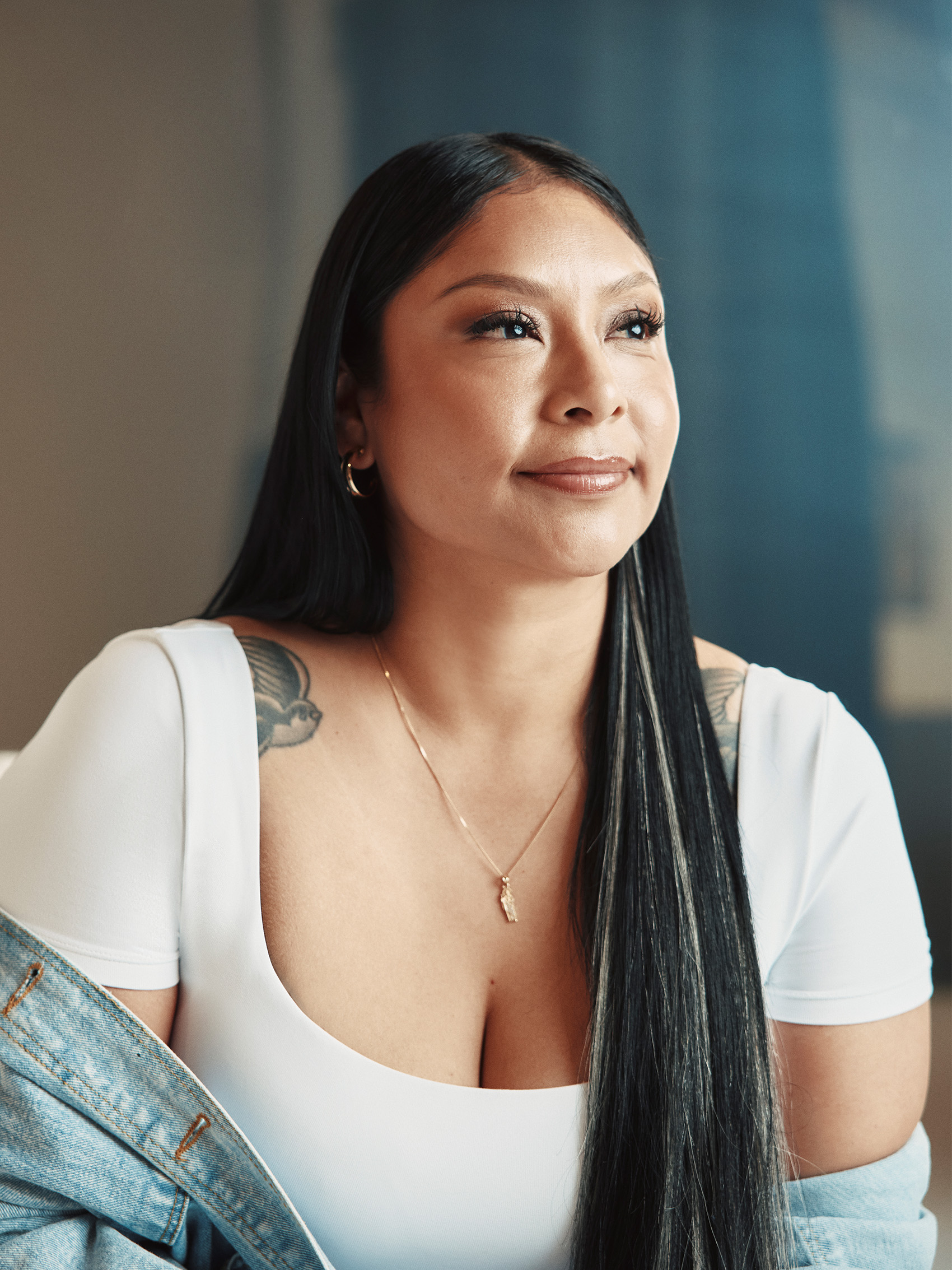 Angelica Vargas seated in a white top and denim jacket, looking off-camera.