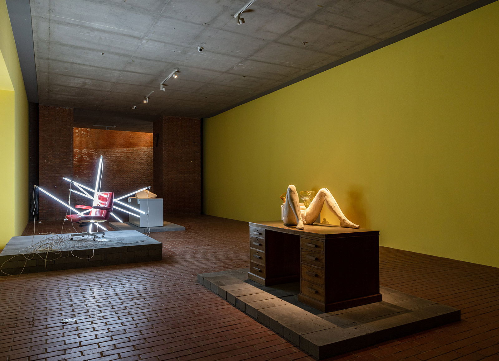 Legs sculpture on desk and red lit up office chair to left