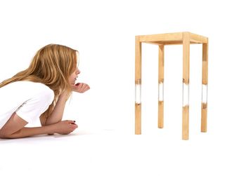 Woman looking at a wooden table with plastic parts connecting the legs