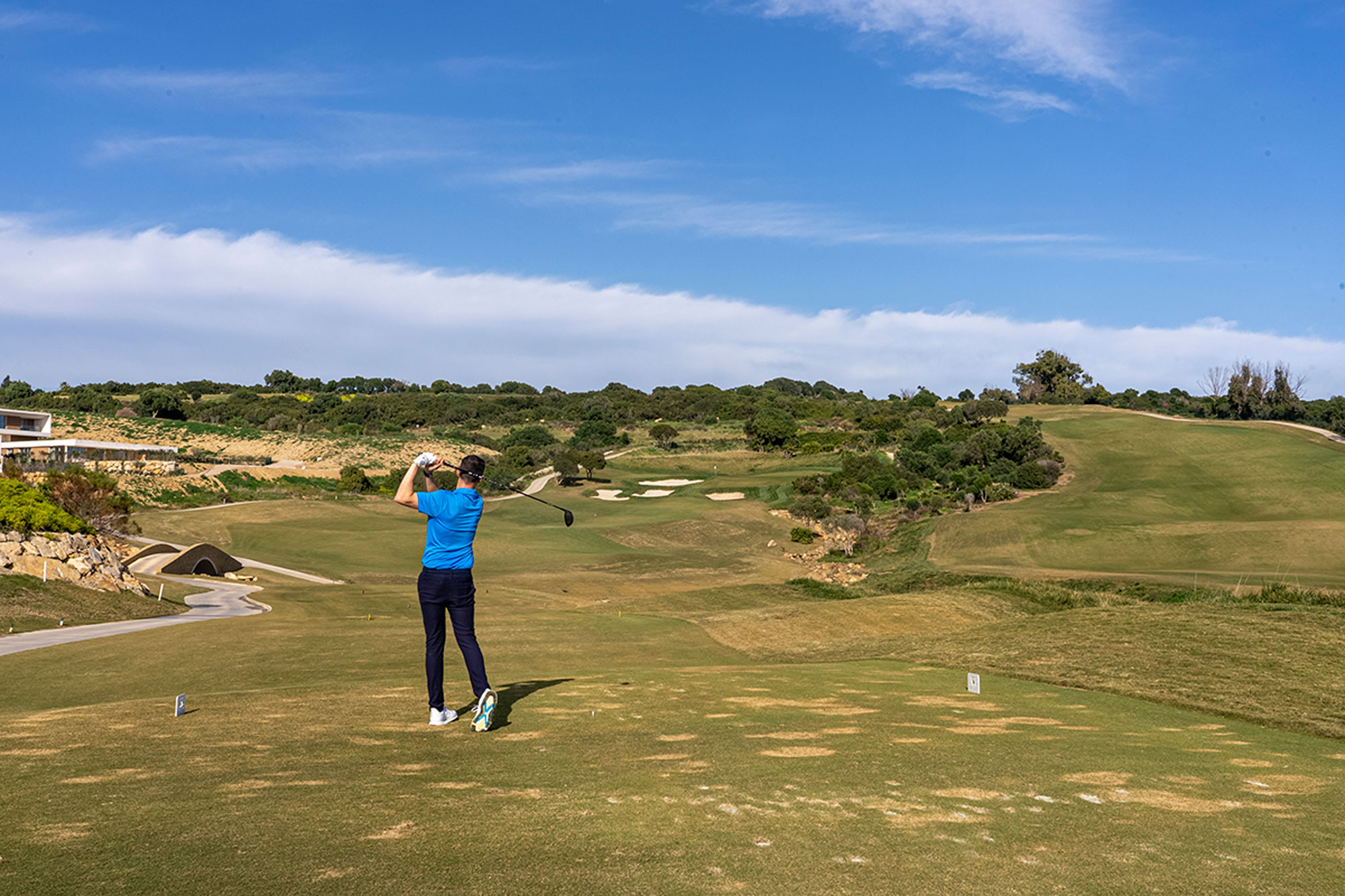 Joel Tadman hitting a tee shot with driver at La Hacienda, holding the finish position as the ball travels away from the tee box