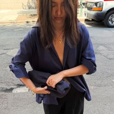 A woman wearing a chic outfit consisting of black trousers and a silky navy shirt