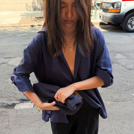 A woman wearing a chic outfit consisting of black trousers and a silky navy shirt