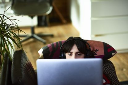 Woman using laptop and wearing headphones