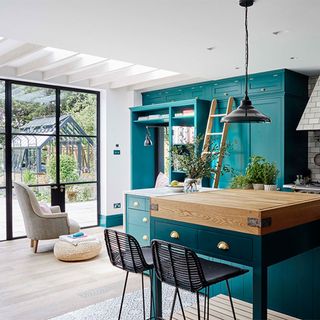 green kitchen with island and wooden flooring