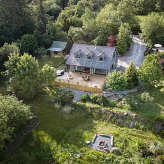 Aerial view of a large tree lined garden and a house with a patio