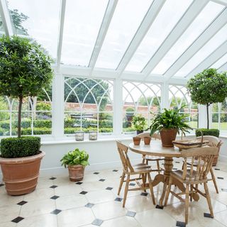 white garden room with table and potted plants