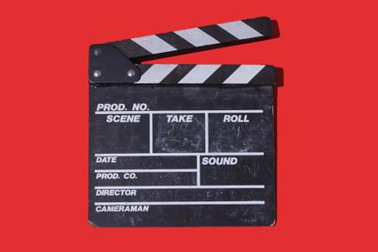 Old wooden movie clapperboard with hard shadow on red background. Concept of film industry, cinema, entertainment, and Hollywood.